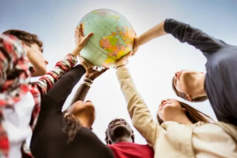 Jóvenes de distintas nacionalidades sujetan una bola del mundo